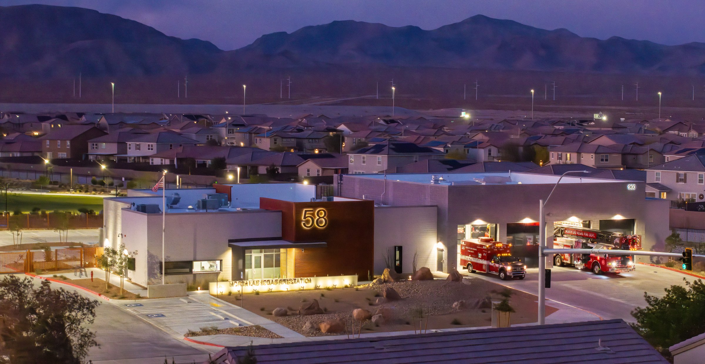 Fire Station 58 at dusk with engines in the bays and mountains beyond